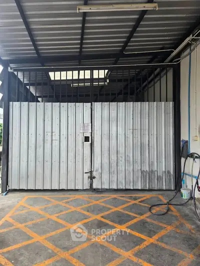 Secure industrial storage unit with metal gate and overhead shelter