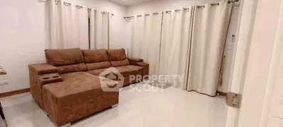 Spacious living room with plush brown sectional sofa and elegant white curtains.