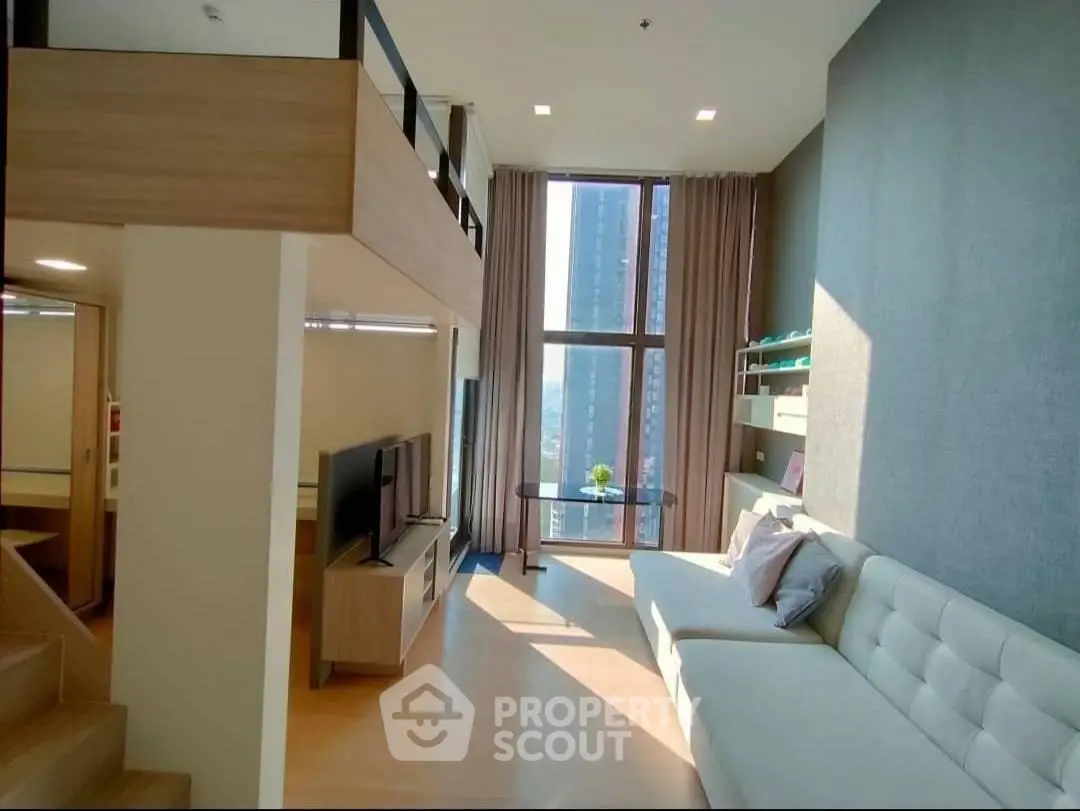 Modern loft-style living room with high ceilings and large windows offering city views.