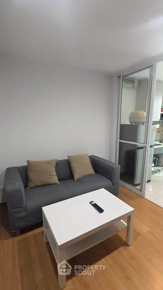 Cozy living room with modern sofa and coffee table, adjacent to a glass partitioned area.