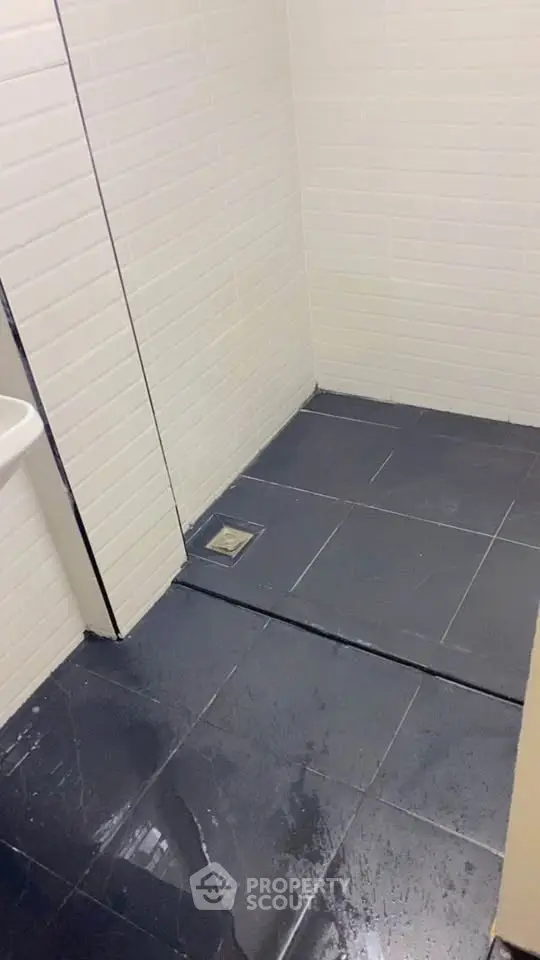 Modern bathroom with sleek black tiles and white walls, featuring a minimalist design.