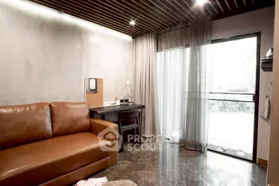 Modern living room with leather sofa and balcony view, featuring sleek design and natural light.