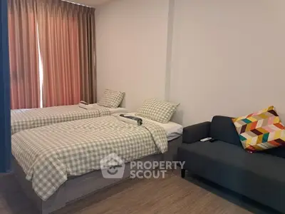 Cozy bedroom with twin beds and modern sofa, perfect for comfortable living.