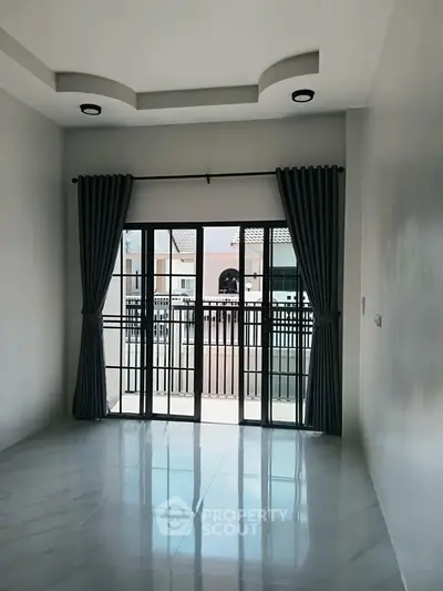 Spacious room with large windows and elegant curtains, offering ample natural light and a modern design.