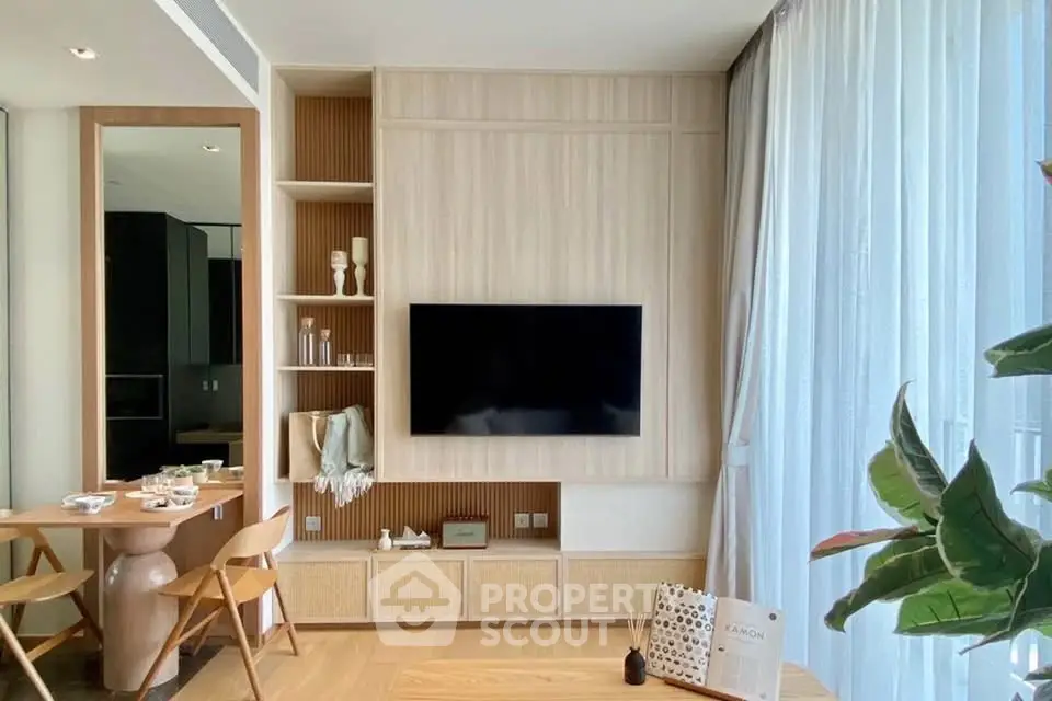 Modern living room with stylish decor and large TV, featuring elegant wooden accents and natural light.