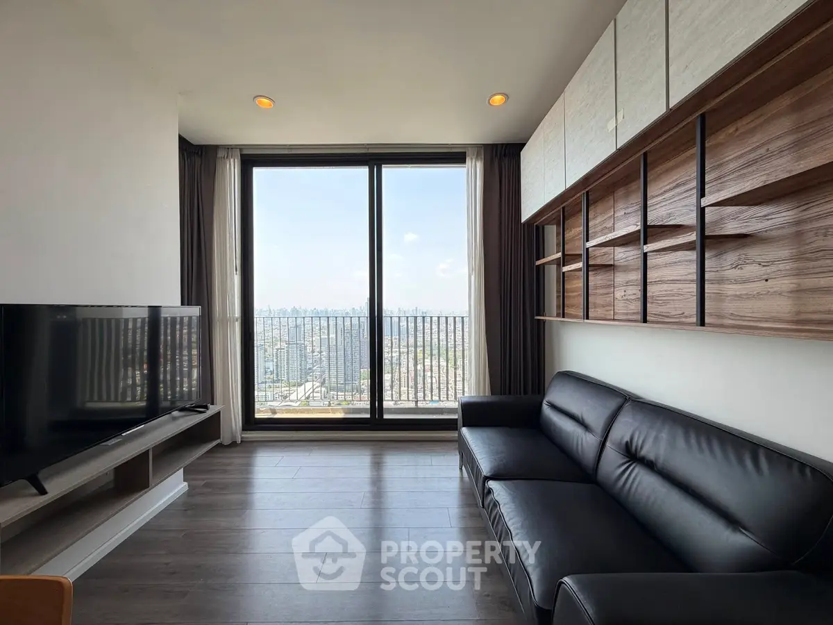 Modern living room with sleek furniture and stunning city view through large window.