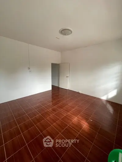 Spacious empty room with glossy wooden flooring and white walls