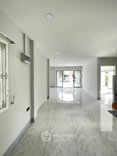 Spacious open-plan living area with marble flooring and large windows for natural light.
