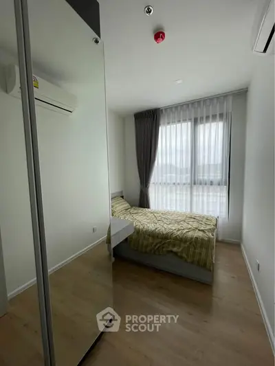 Modern bedroom with large window and mirrored wardrobe in stylish apartment