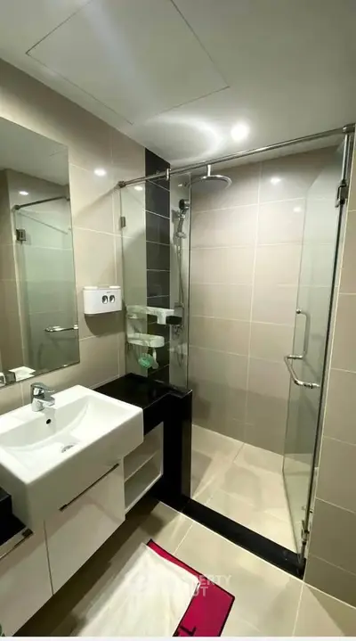 Modern bathroom with glass shower and sleek fixtures in contemporary apartment.