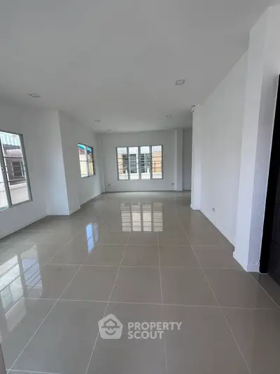Spacious open-plan living area with large windows and glossy tiled floors, perfect for modern living.