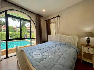 Cozy bedroom with pool view and elegant arched window design.