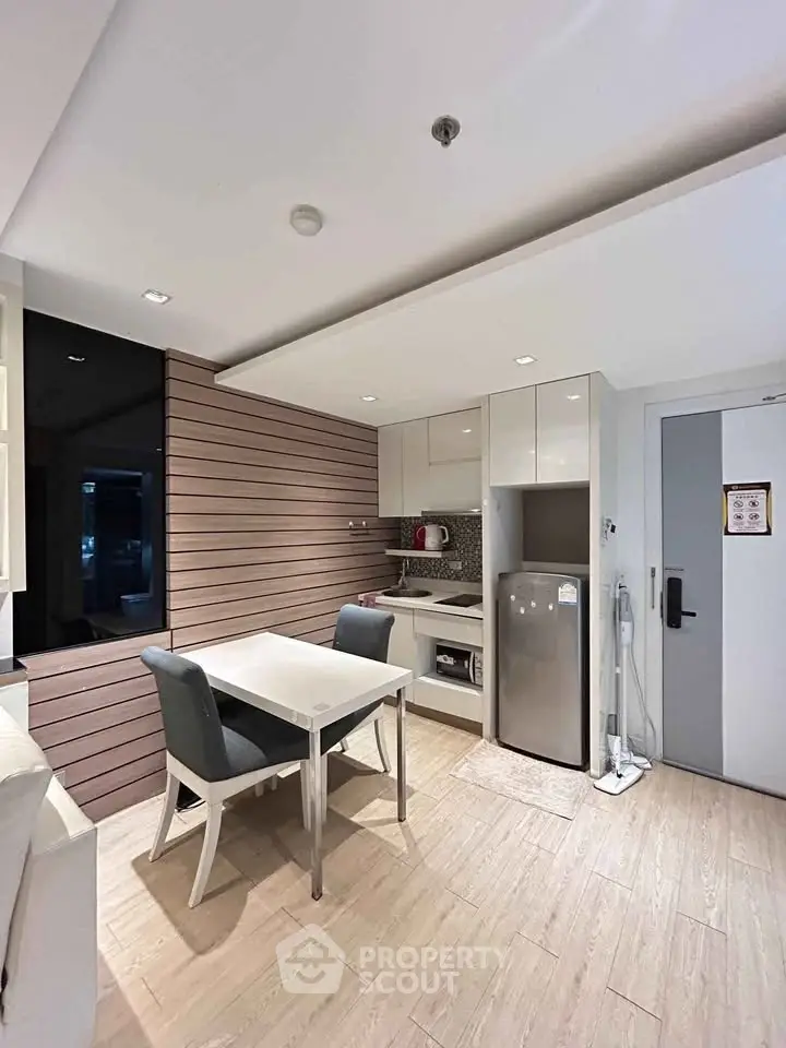 Modern kitchen with dining area, featuring sleek cabinetry and stainless steel appliances.