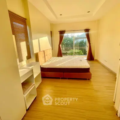 Spacious bedroom with large windows and balcony access, featuring modern decor and natural light.