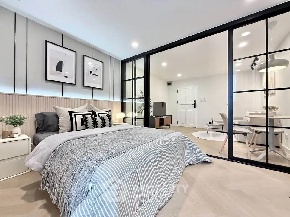 Modern bedroom with stylish decor and glass partition leading to living area.