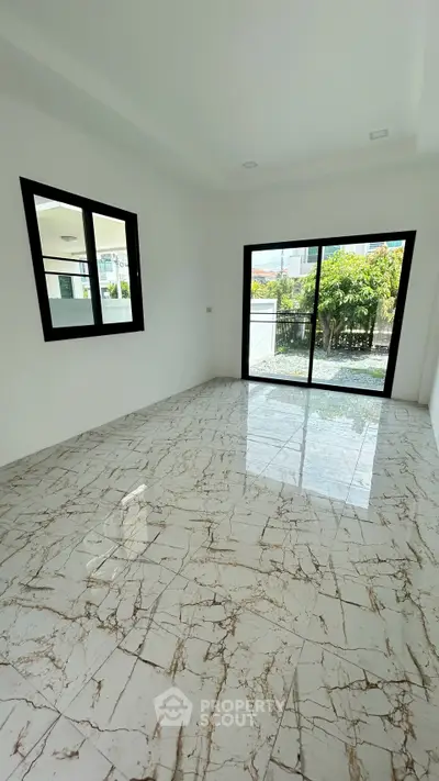 Spacious room with marble flooring and large windows offering garden view