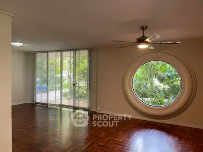 Spacious living room with unique circular window and garden view