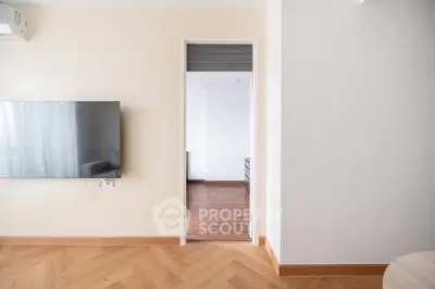 Modern interior with sleek TV and wooden flooring, showcasing open layout and bright ambiance.