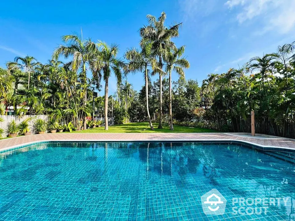 Luxurious tropical poolside with lush palm trees and clear blue sky