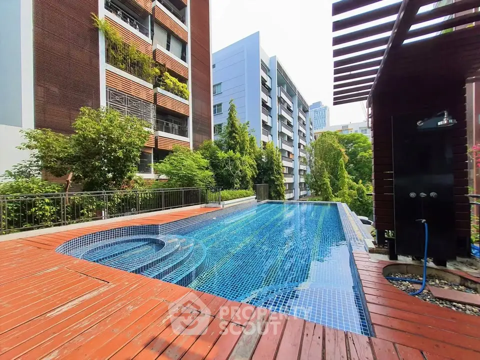 Luxurious outdoor pool area with modern apartment buildings and lush greenery.