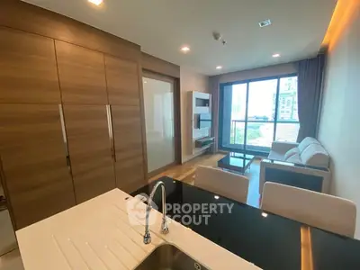 Modern living room with open kitchen and city view, featuring sleek design and natural light.