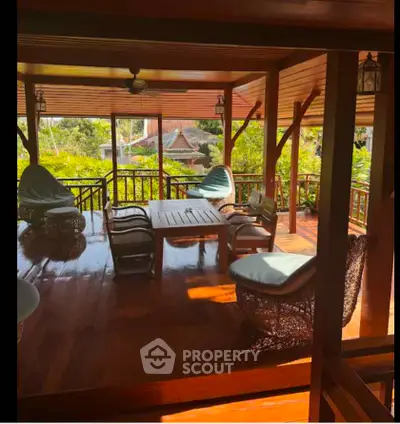 Spacious wooden balcony with cozy seating and lush garden view, perfect for relaxation and entertaining.