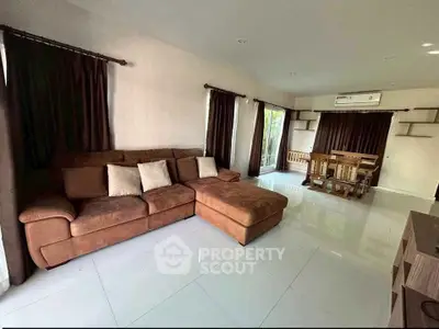 Spacious living room with modern brown sofa and dining area, perfect for family gatherings.