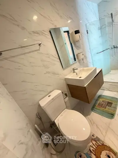 Modern bathroom with sleek fixtures and marble walls, featuring a glass shower and stylish vanity.