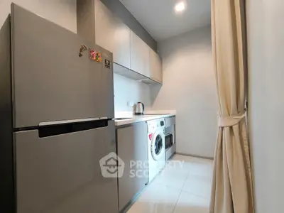 Modern kitchen with sleek appliances and washing machine in compact layout.