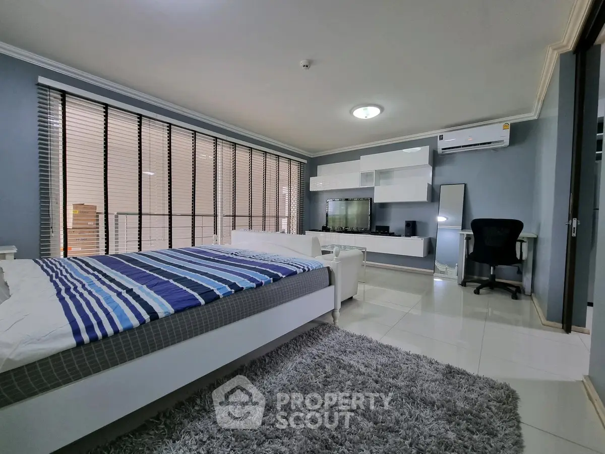 Spacious modern bedroom with stylish decor and large windows for natural light.