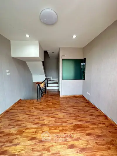 Spacious modern living room with wooden flooring and stylish staircase, perfect for contemporary living.