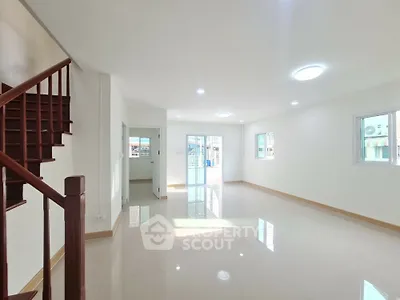 Spacious modern living room with natural light and staircase in a bright home