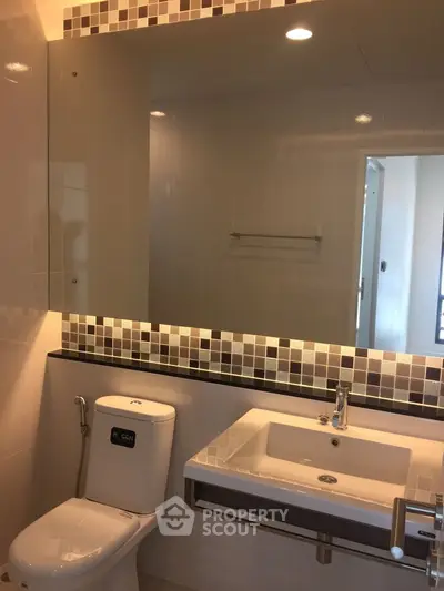 Modern bathroom with sleek fixtures and large mirror in a contemporary apartment.