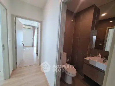 Modern apartment hallway with bathroom and bedroom access, featuring sleek design and natural lighting.