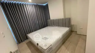 Modern bedroom with sleek design and floor-to-ceiling curtains, featuring a comfortable bed and wooden flooring.