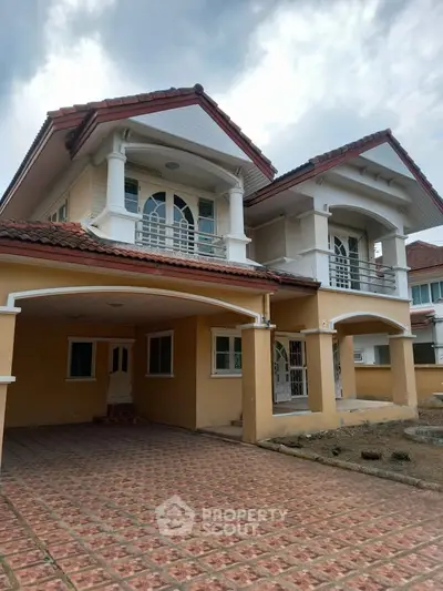 Charming two-story house with tiled driveway and arched windows, perfect for family living.