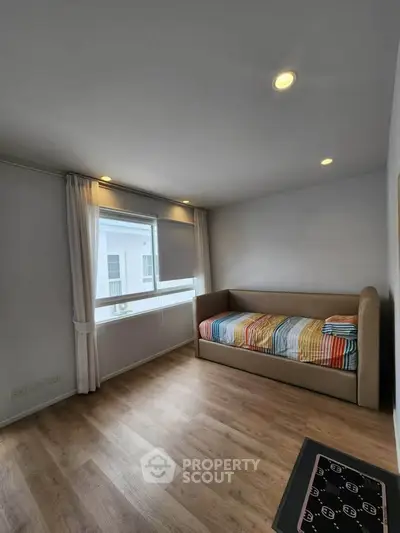 Bright and cozy bedroom with modern decor and wooden flooring, perfect for relaxation.