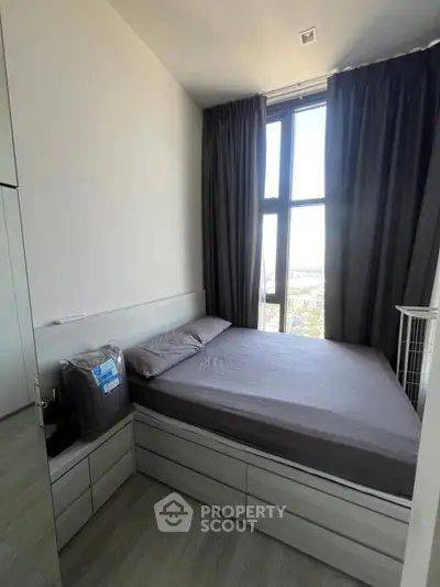 Modern bedroom with large window and sleek storage solutions in a high-rise apartment.