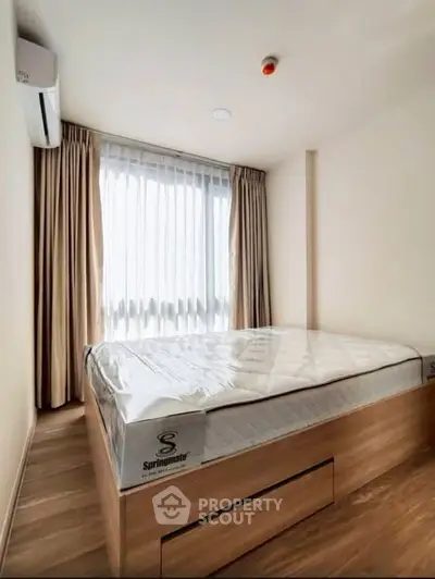 Modern bedroom with natural light and stylish wooden flooring, featuring a comfortable bed and elegant curtains.