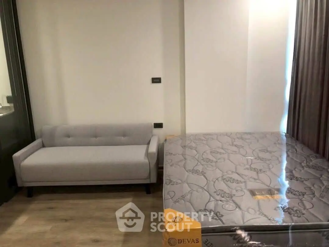 Modern bedroom with stylish gray sofa and new mattress in a cozy apartment.