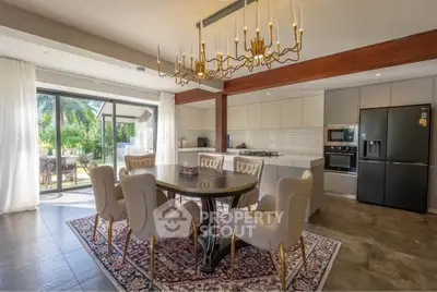 Luxurious open kitchen and dining area with elegant chandelier and garden view.