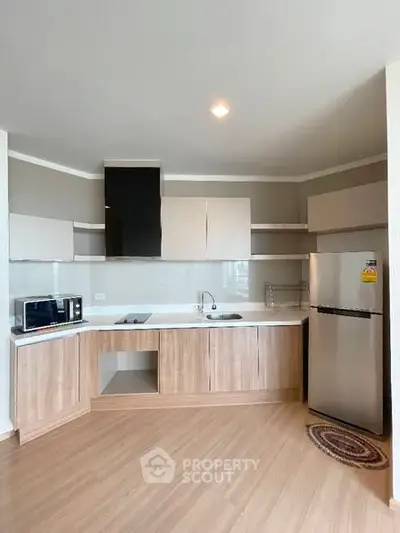 Modern kitchen with sleek cabinets, stainless steel fridge, and microwave in a stylish apartment.