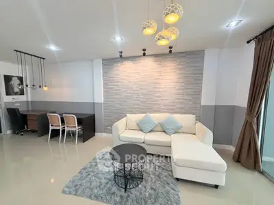 Modern living room with stylish decor, featuring a cozy white sofa, elegant lighting, and a chic workspace.