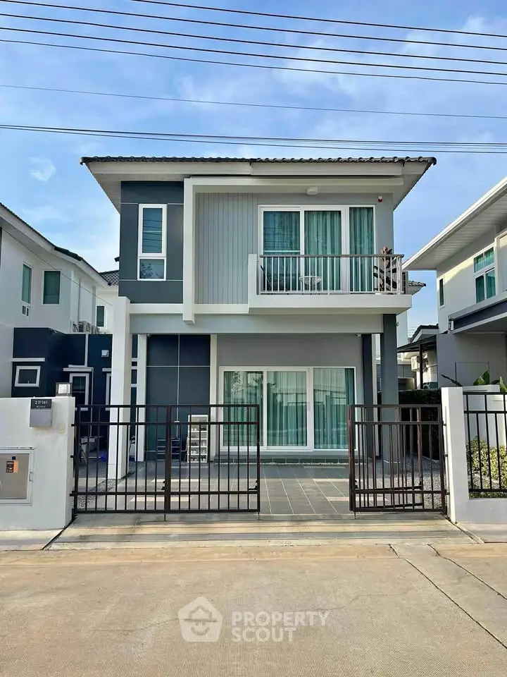 Modern two-story house with sleek design and small balcony in a suburban neighborhood.