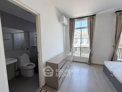 Bright bedroom with balcony access and adjacent bathroom, featuring modern furnishings and natural light.