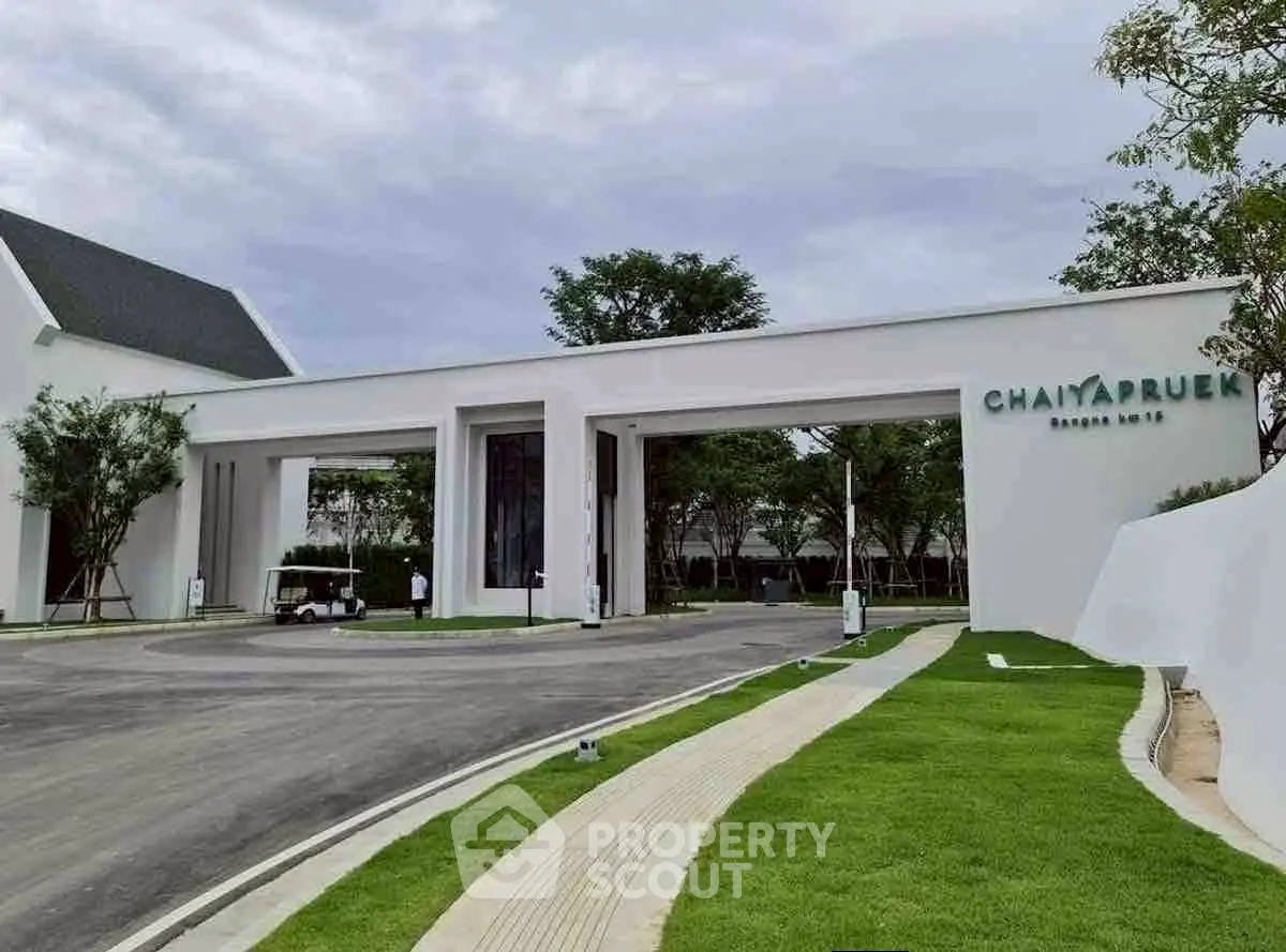 Elegant entrance of Chaiyapruek housing complex with modern architecture and lush greenery.