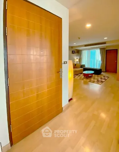 Spacious living room with modern decor and wooden flooring, featuring a cozy seating area and ambient lighting.