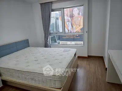 Spacious bedroom with large window and natural light in modern apartment.