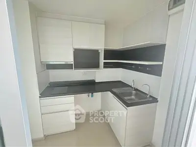 Modern compact kitchen with sleek cabinetry and integrated sink in a stylish apartment.