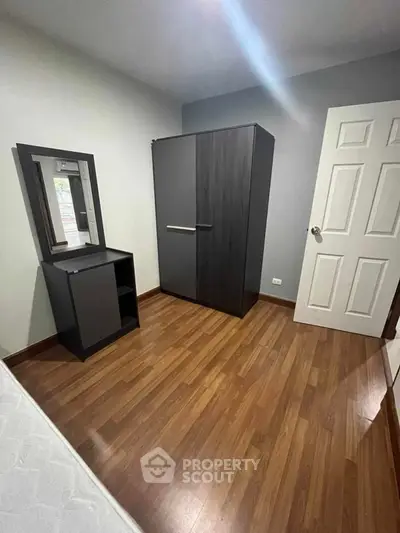 Cozy bedroom with modern wardrobe and wooden flooring, perfect for a minimalist lifestyle.